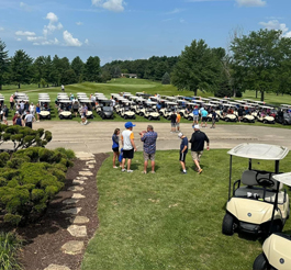 An open golf tournament where many golf carts are visible and people are walking around.