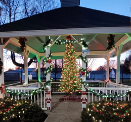 A gazebo decorated with Christmas lights, inside the gazebo is a lit Christmas tree.